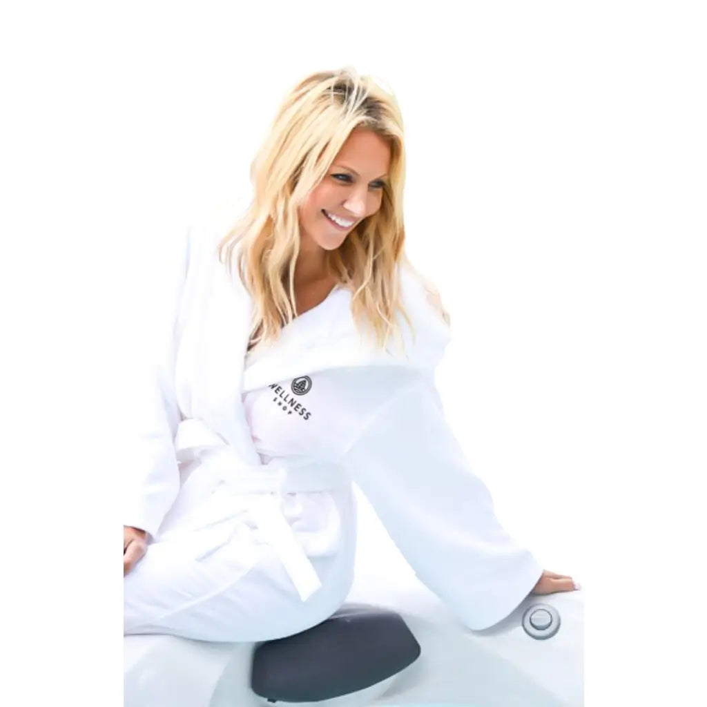Woman wearing a white robe with the Wellness Shop logo